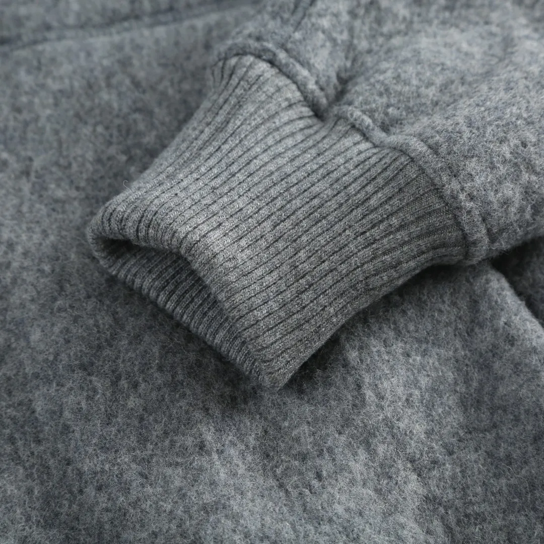 P780 Canada Goose Fleece Badge Hooded Jacket Fabric selection: Wool fleece fabric blended with wool as the main body and a very small amount of spandex and polyester fibers. Wool is a core natural ingredient that provides unparalleled temperature regulation, antibacterial and anti-odor properties and a skin-friendly feel. The feeding of a small amount of spandex gives the fabric a certain degree of four-way elasticity, making it non-restrictive during daily activities. As the basis of fleece's structure, polyester fiber enhances the fabric's durability, wrinkle resistance and quick-drying properties. It contributes to the loft of the fleece and provides functions such as trapping air.  Detail 1: The sleeves and hem are closed with 2×2 ribbing. Its strong elasticity can closely fit wrists and waists of different thicknesses, forming an effective 'seal' to prevent cold wind from blowing back. It can still maintain its original shape after repeated stretching and use, and is not easy to loose and deform. And the ribbed cuffs can convey a sense of design and enhance the visual beauty.  Detail 2: The combination of hood design and elastic buckle improves warmth and windproof performance when wearing.  Accessories: 1:1 customized elastic drawstring buckle, 1:1 customized zipper pendant, 1:1 customized armband SIZE: S M L XL